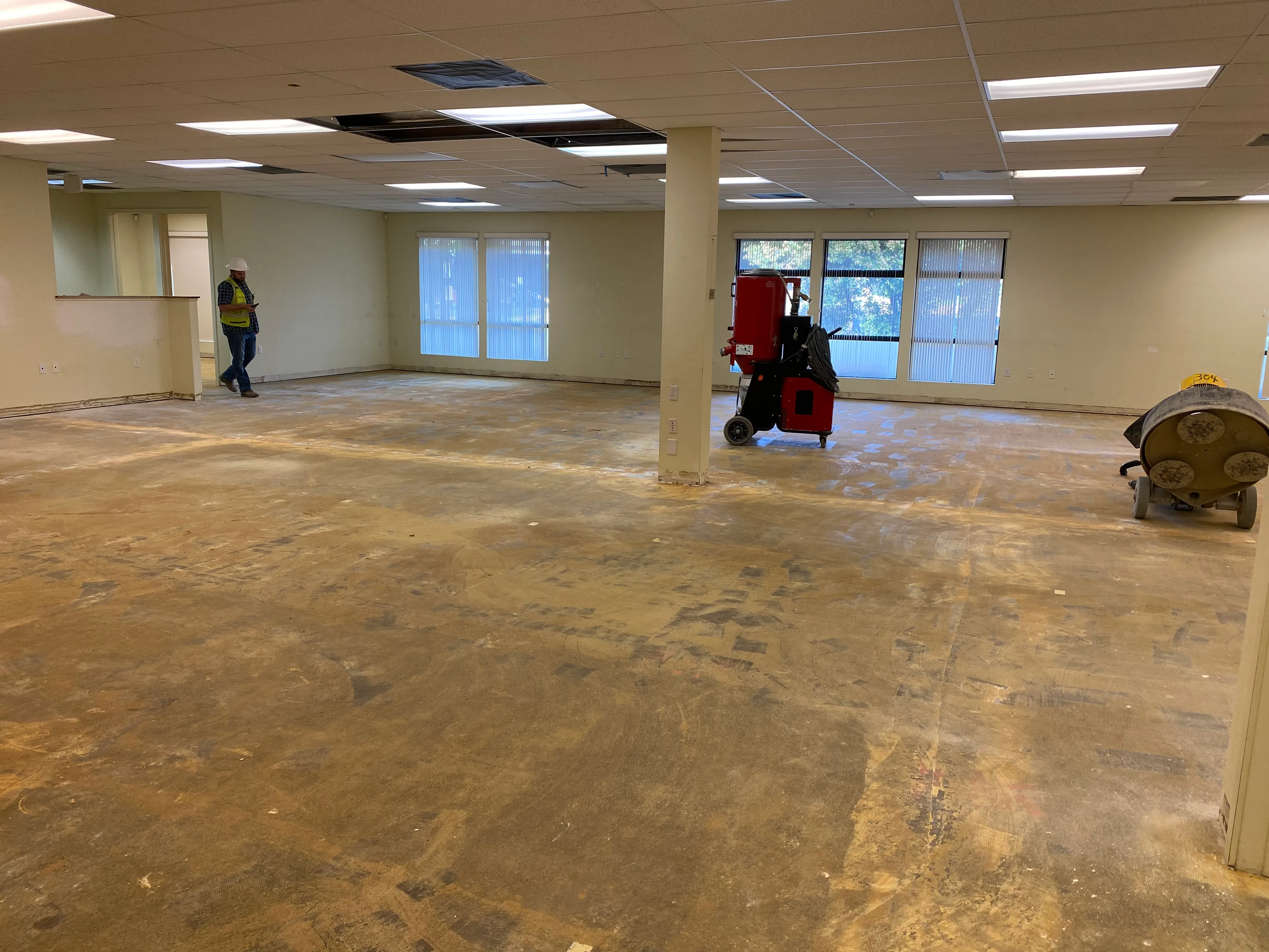 Interior of 3001 E Street during initial remodel with floor grinding equipment and columns in open office space