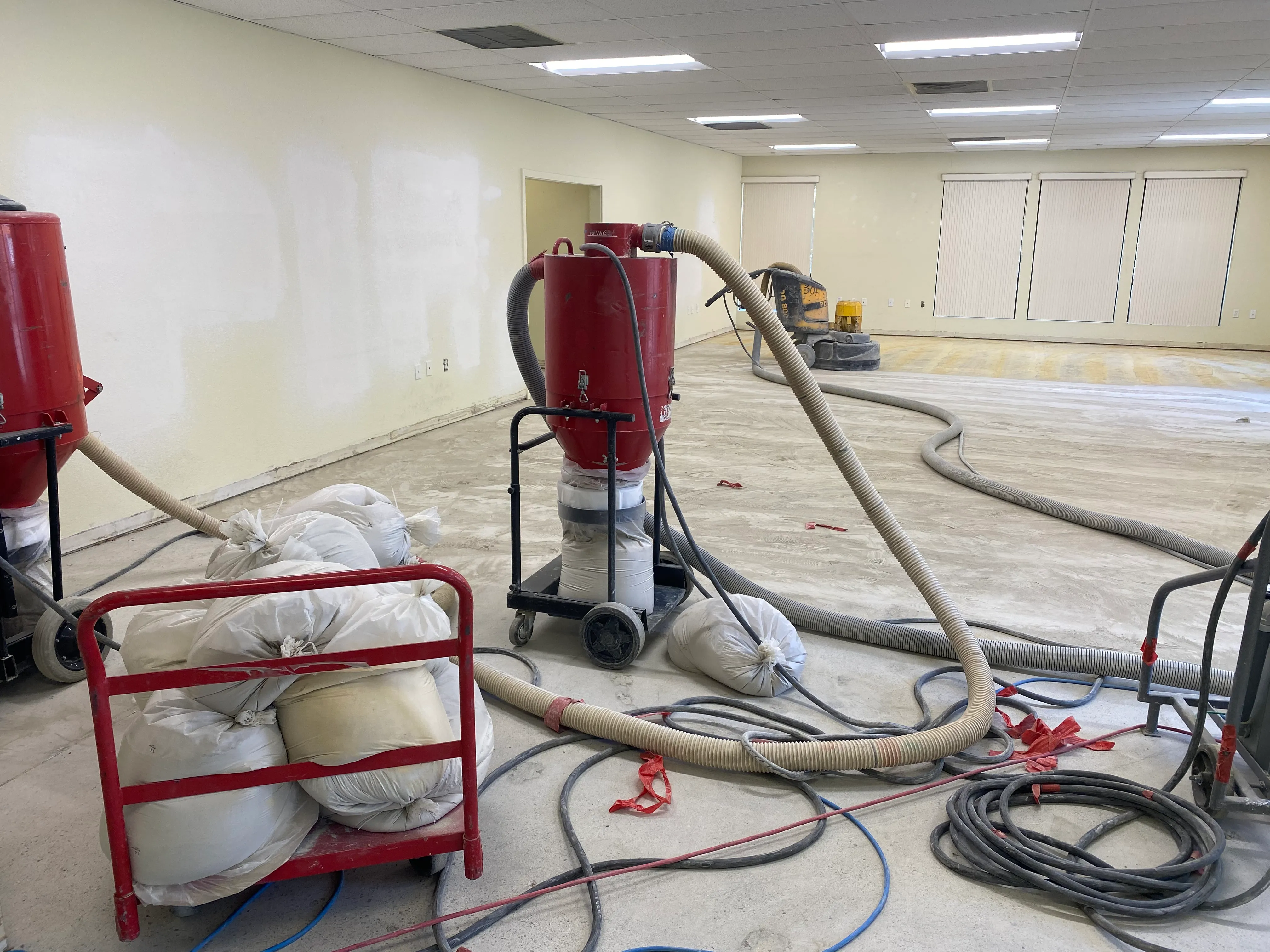 Industrial concrete floor grinding and dust collection equipment inside 3001 E Street during office renovation