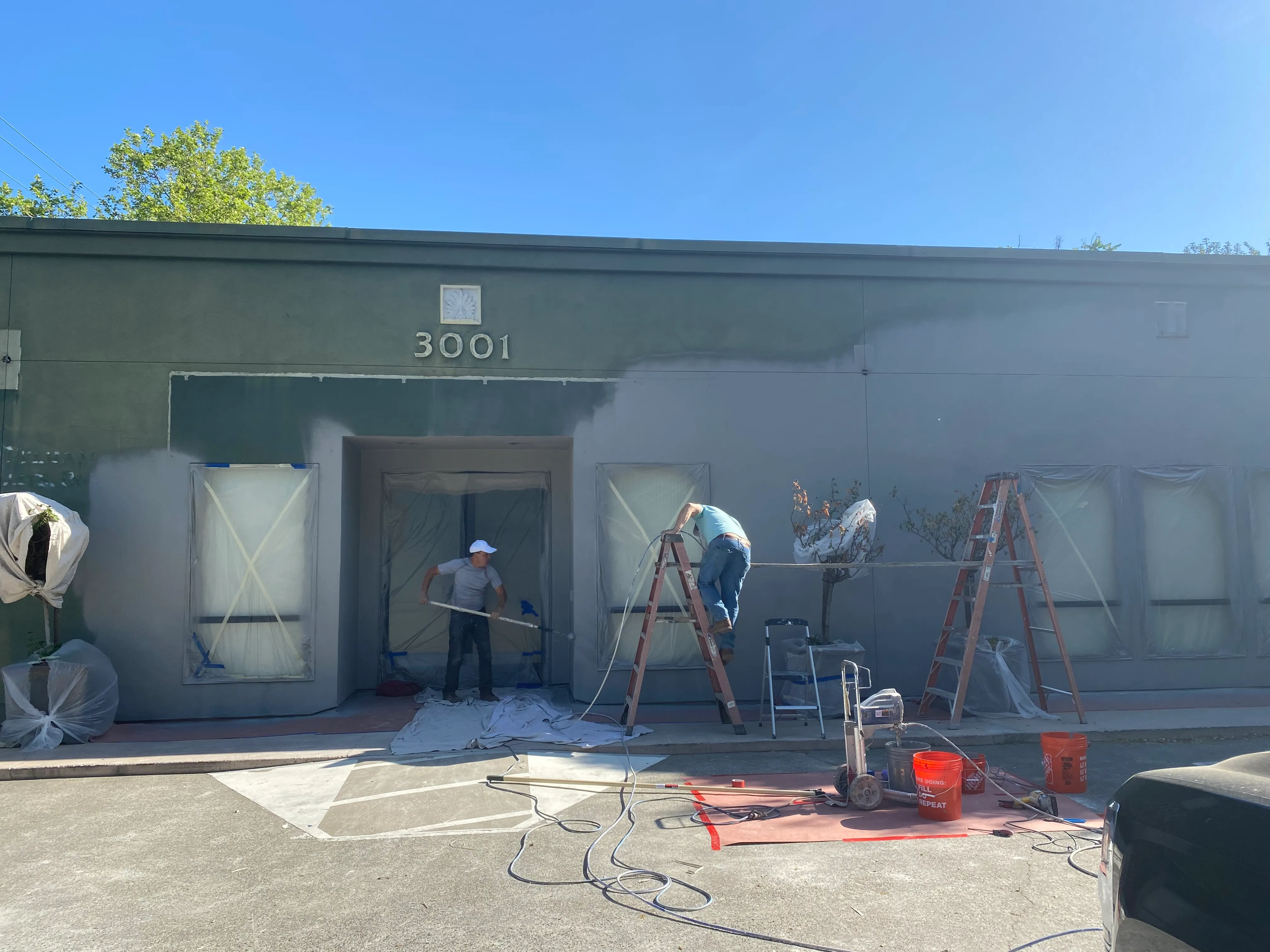 Workers painting the exterior facade of 3001 E Street dark gray during office renovation