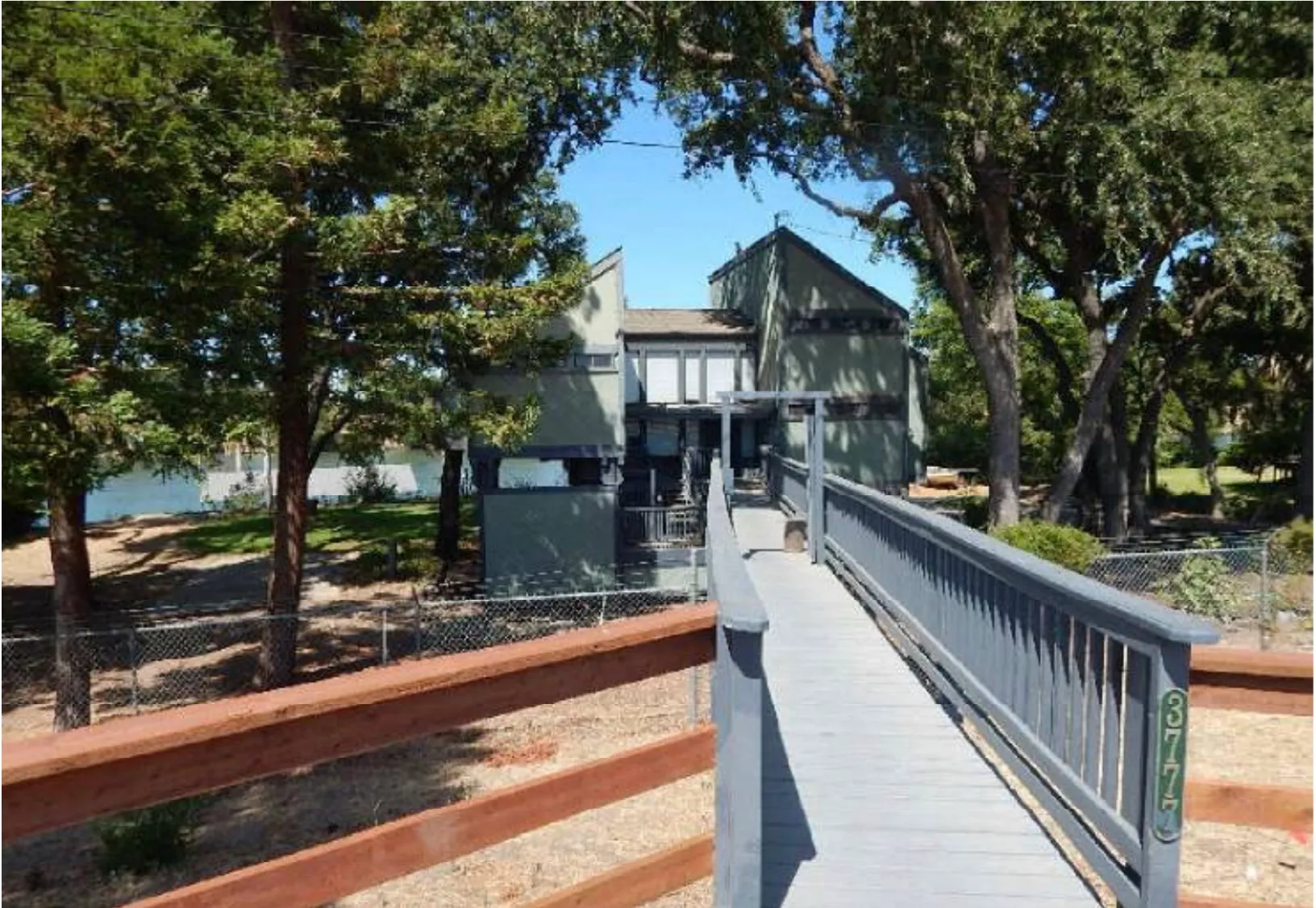 Original entry footbridge at 3777 Garden Highway with weathered railings and chain-link fencing