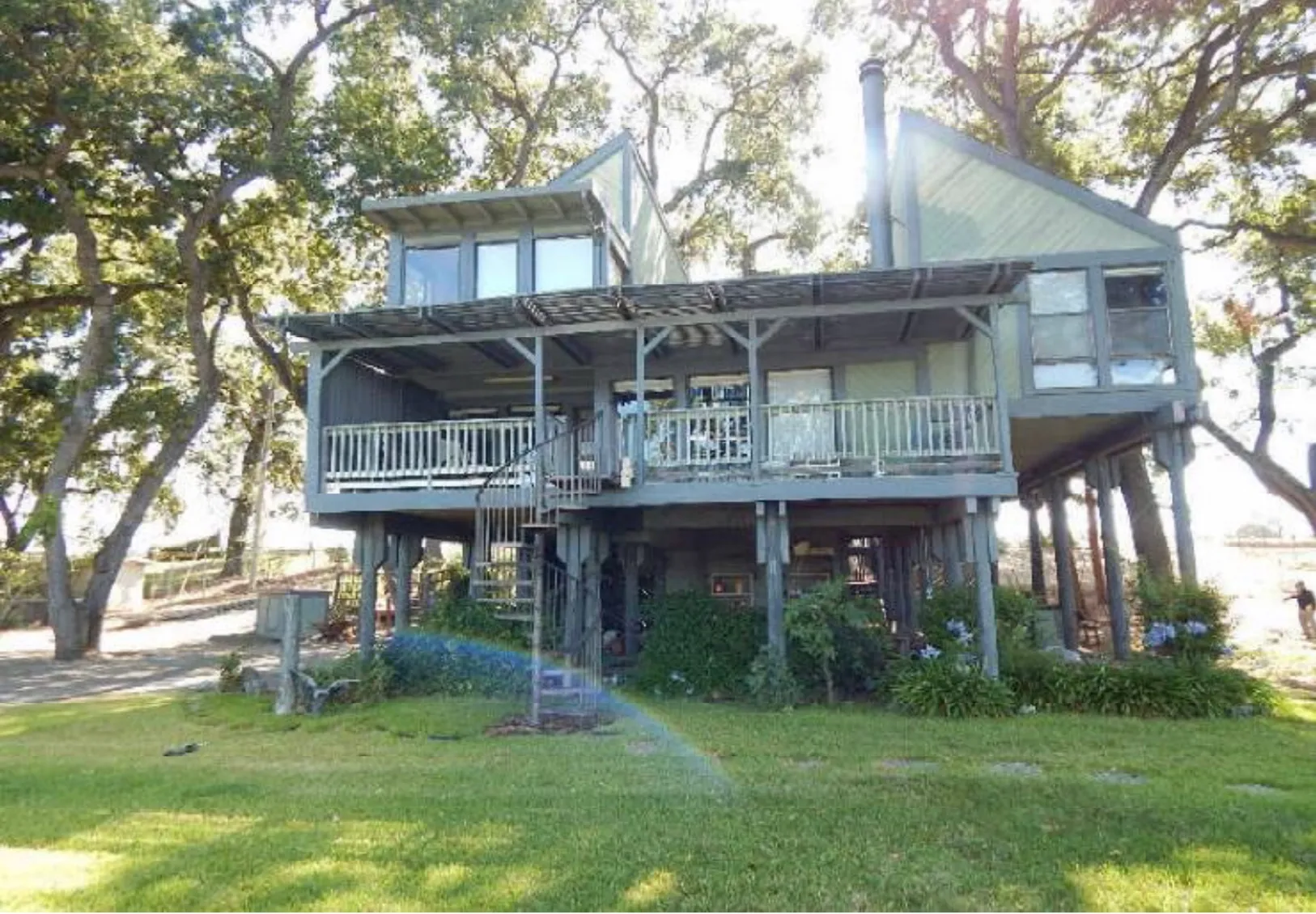3777 Garden Highway before renovation - dated gray-green elevated home with worn decks and railings