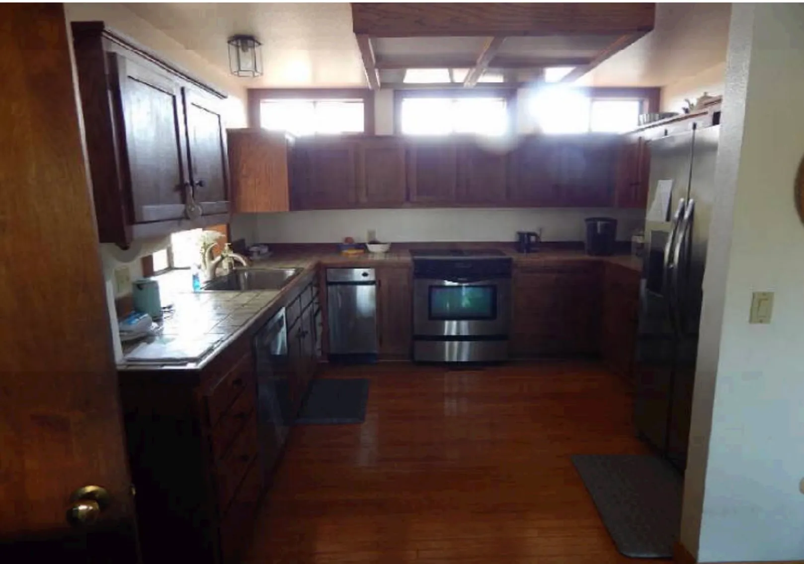 Kitchen before renovation with dark oak cabinets, tile counters, and closed-in layout