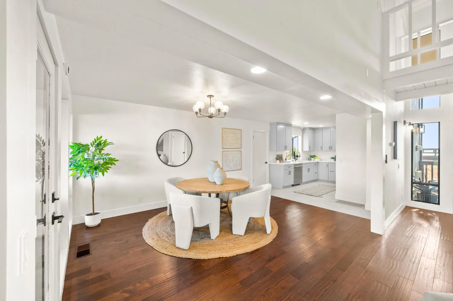 Dining area with round wood table opening to the renovated kitchen and two-story entry