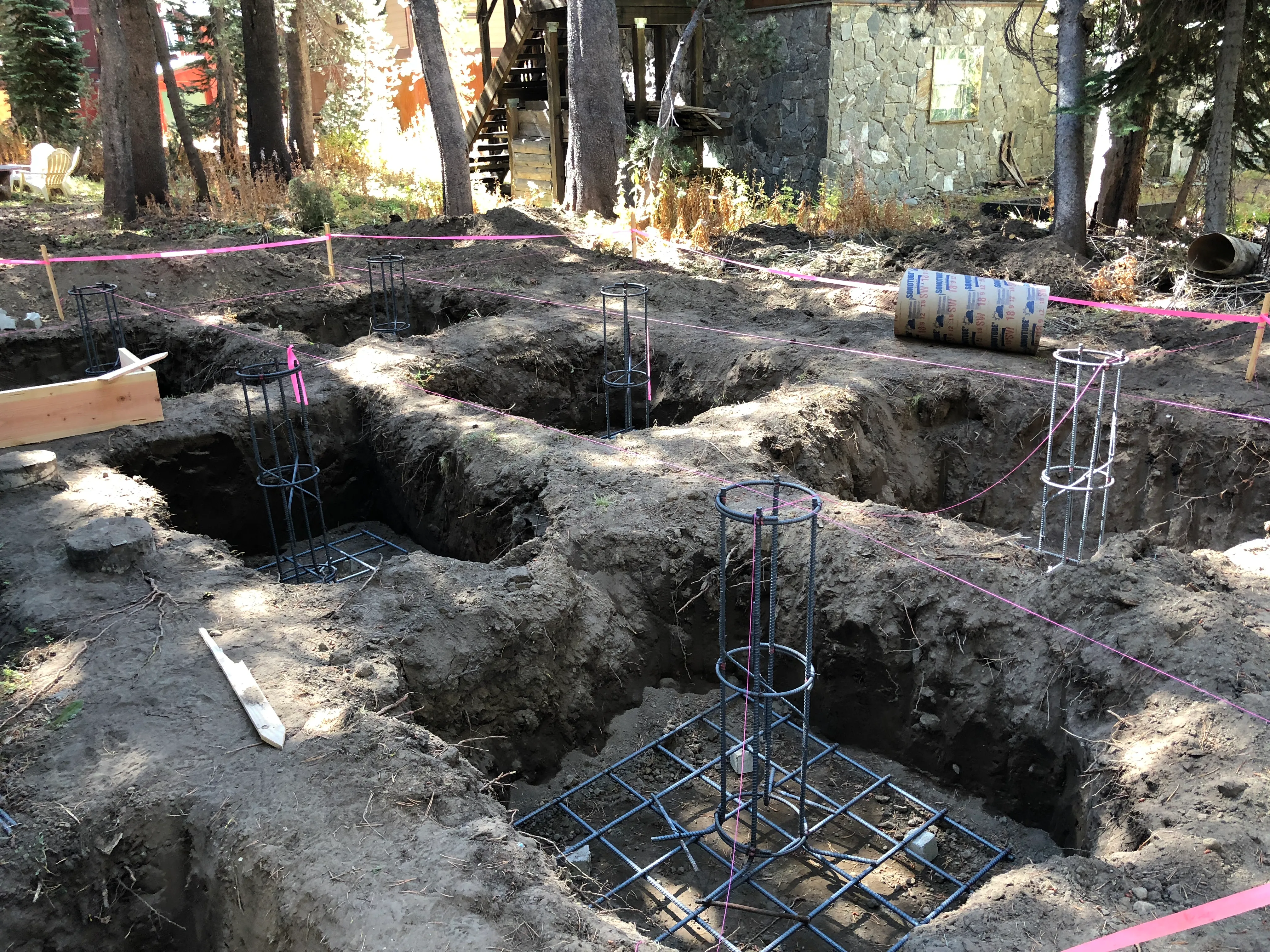 Foundation excavation with rebar columns and sonotubes among pine trees at the build site