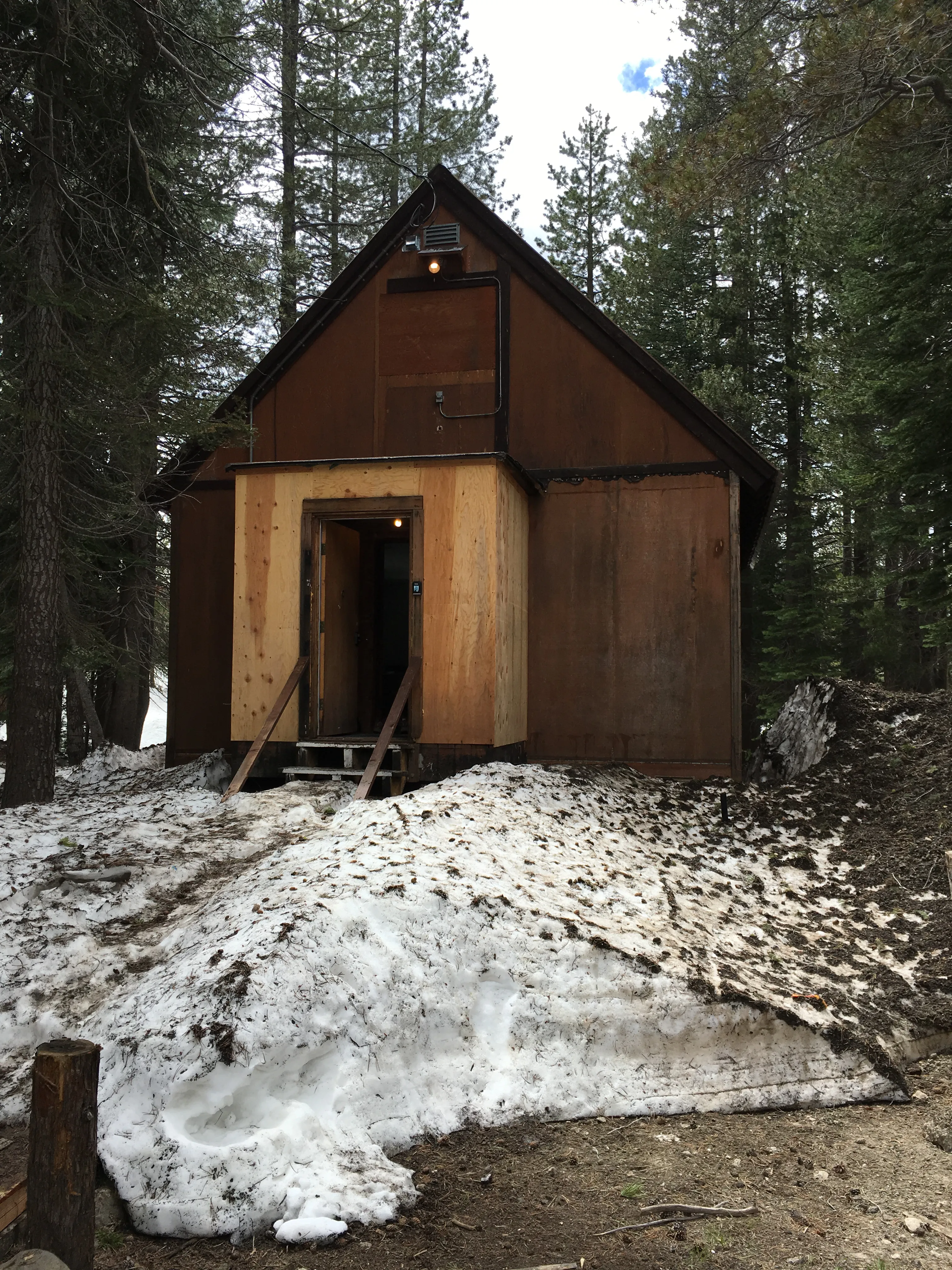 Original A-frame cabin in Soda Springs surrounded by snow and pine trees before renovation