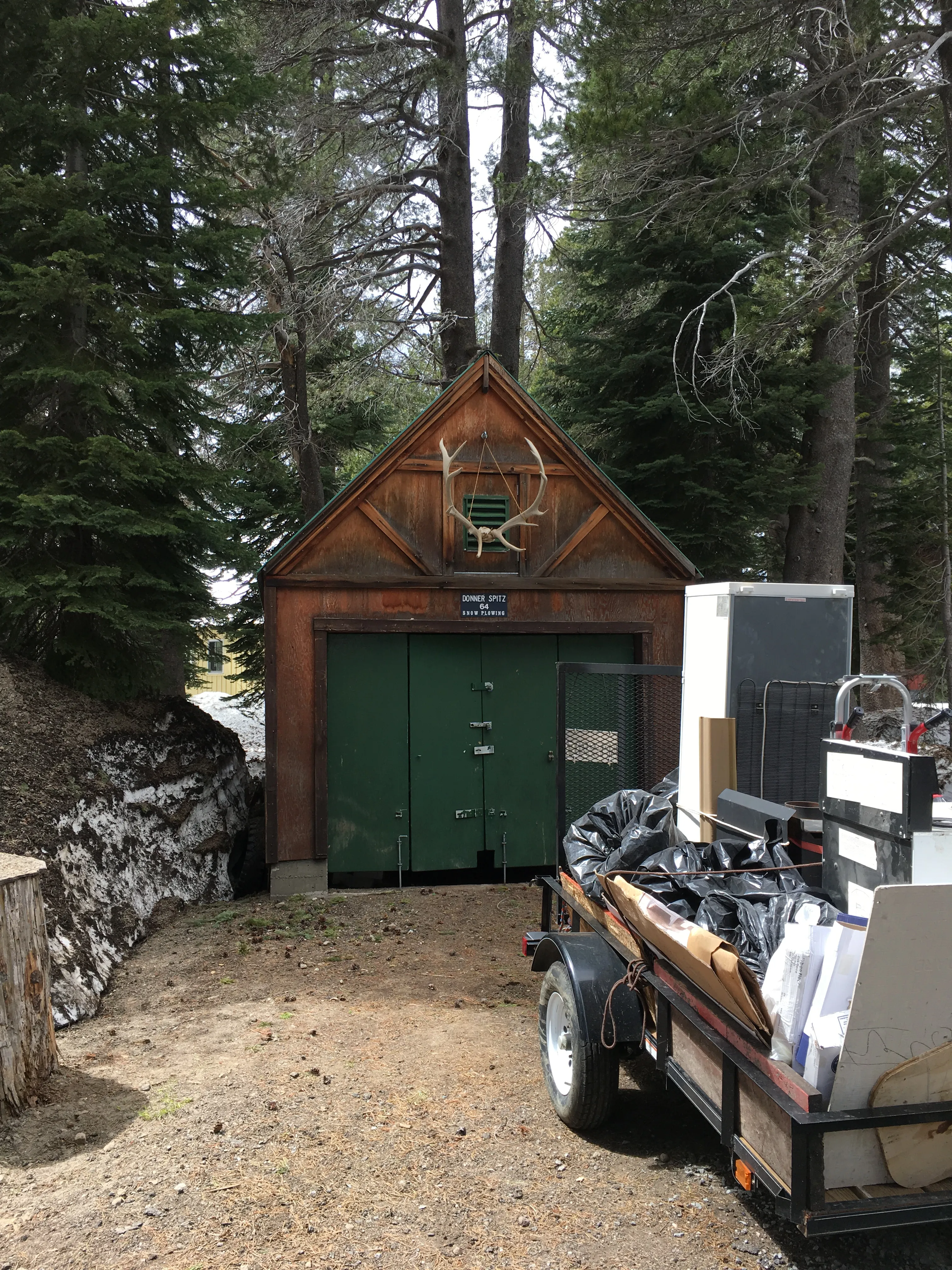 Original detached garage with A-frame peak and green doors before demolition