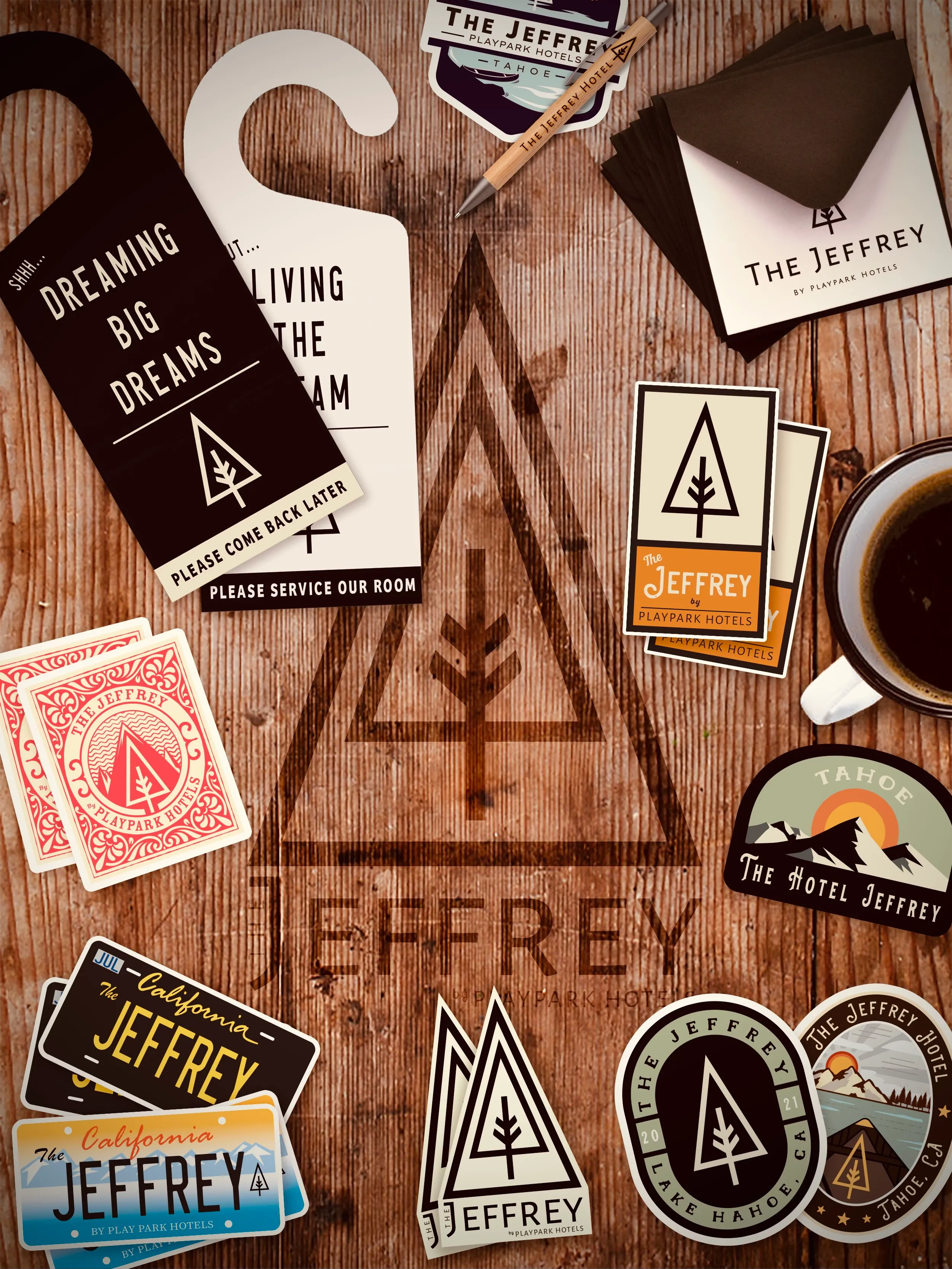 The Jeffrey Hotel brand identity - custom merchandise, signage, door hangers, stickers, and playing cards on wood surface